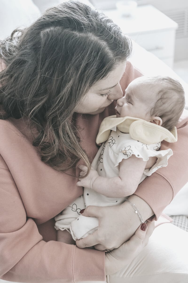 Mother kissing sleeping newborn baby